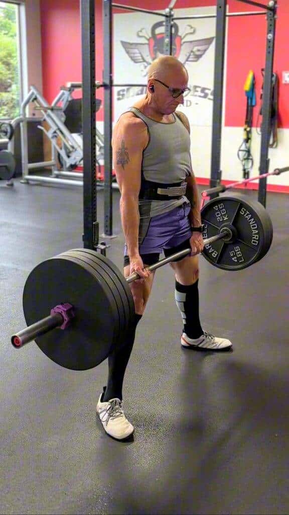 Older man deadlifting heavy weights in gym