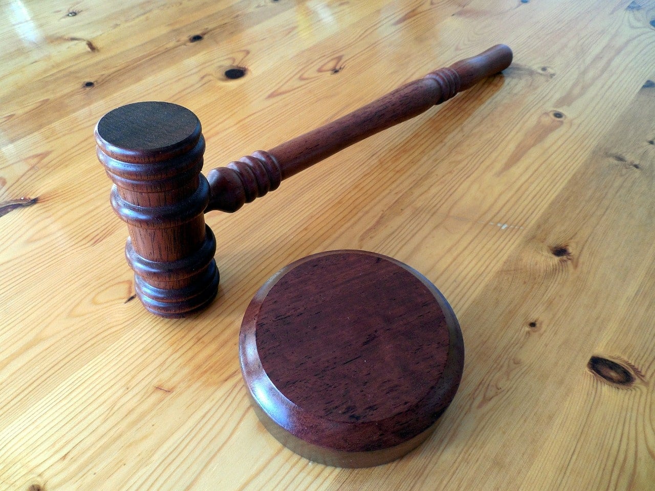 A judge's gavel resting on a wooden sound block on a desk, symbolizing the act of taking an oath.